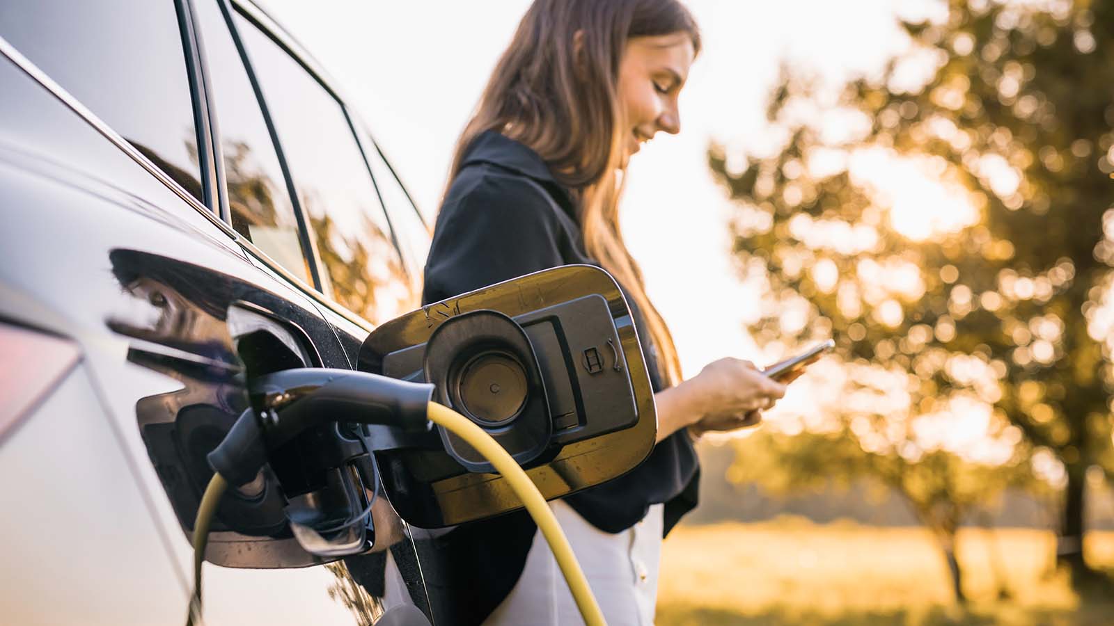 elbil-lader-natur-kvinde-paa-mobil
