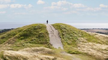 Person står på toppen af "Tre Høje" og kigger ud over Mols Bjerge og Fuglsø Vig