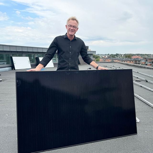 Lars Ibsen på toppen af sparekassens bygning på Markedsvej i Aars med ét af de i alt 122 solpaneler, der for nyligt er blevet monteret på ejendommens tag.