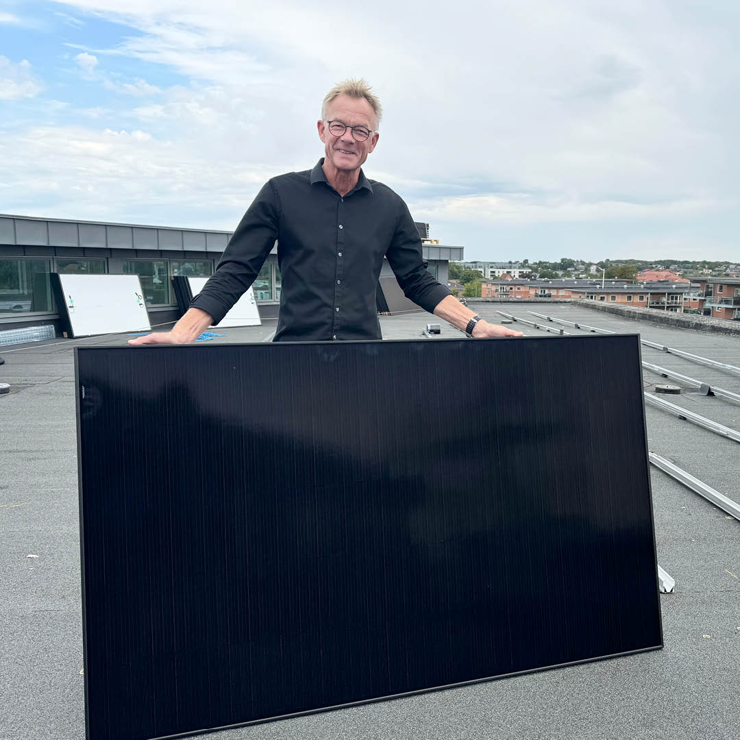 Lars Ibsen på toppen af sparekassens bygning på Markedsvej i Aars med ét af de i alt 122 solpaneler, der for nyligt er blevet monteret på ejendommens tag.